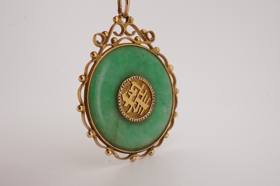 A Chinese yellow metal mounted carved jade 'Shou Fu' pendant, 36mm, on a gilt metal chain. Condition - fair to good